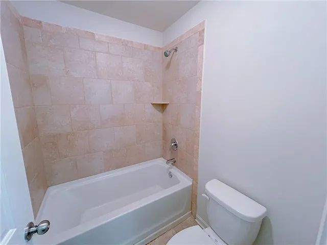 a bathroom with a granite countertop bathtub shower and toilet