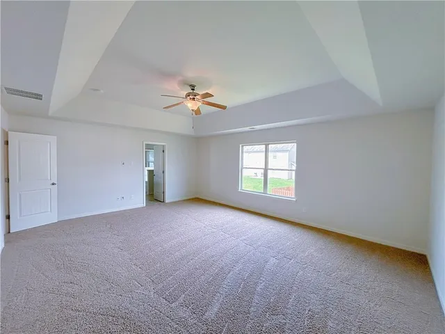an empty room with windows and chandelier fan