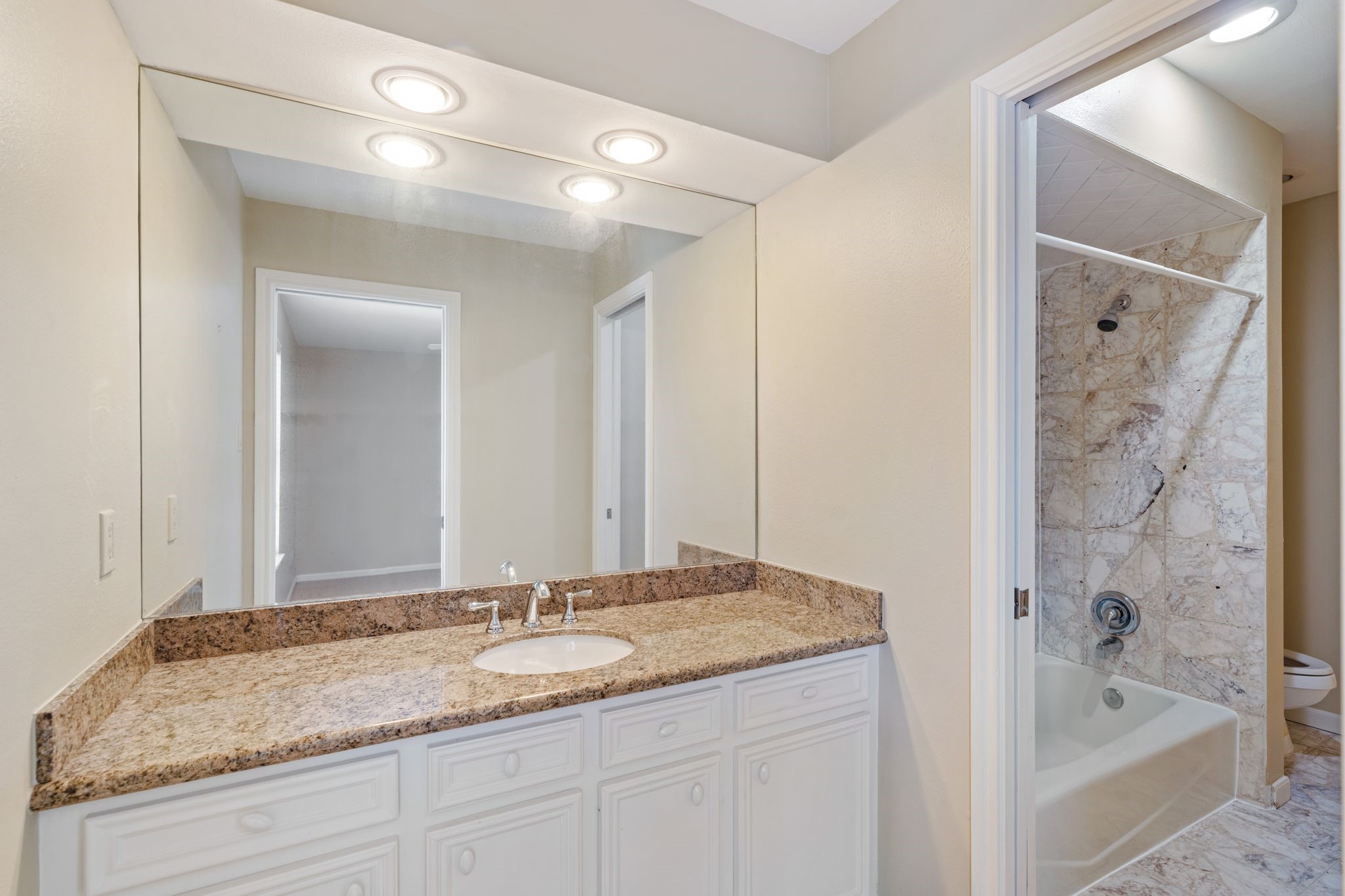 7416 Kelving Street Houston, TX 77030 - Photo 31 of 35 a bathroom with a granite countertop sink tub shower and a mirror