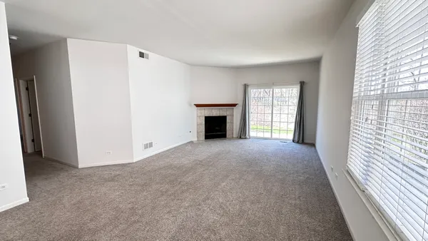 an empty room with windows and fireplace