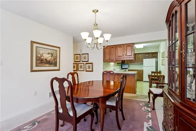 a dining room with wooden floor a chandelier a wooden table and chairs