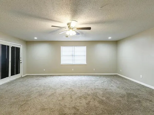 an empty room with windows and chandelier fan