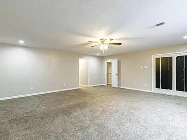 a view of an empty room with a chandelier fan