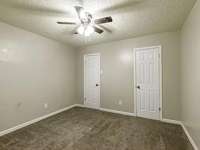 an empty room with windows and fan