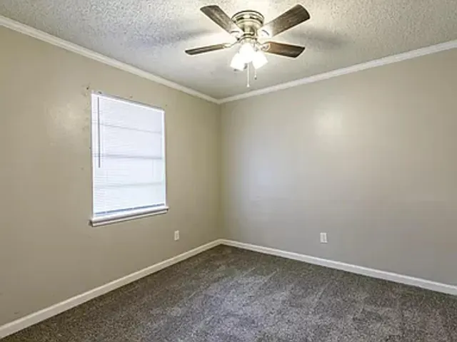 an empty room with a window and a fan