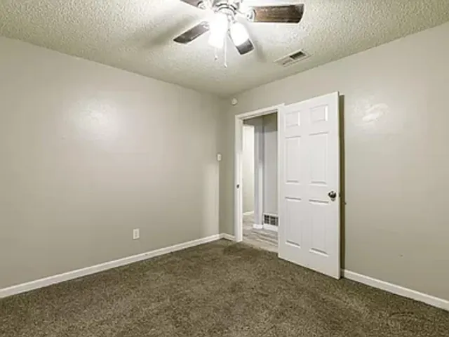 an empty room with chandelier fan