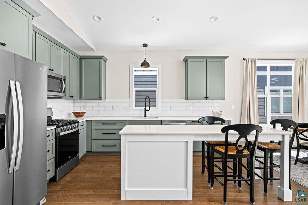 2236 Hoover Street Duluth, MN 55811 - Photo 9 of 52 Kitchen with green cabinetry, stainless steel appliances, a breakfast bar, dark wood finished floors, and pendant lighting