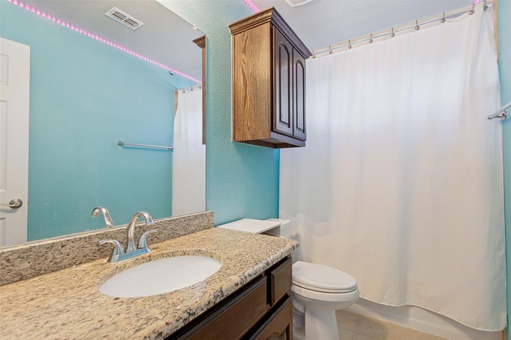 4117 Autumn Path Road Denton, TX 76208 - Photo 10 of 14 Bathroom featuring a granite countertop vanity with an undermount sink, chrome faucet, and wood-finish cabinetry