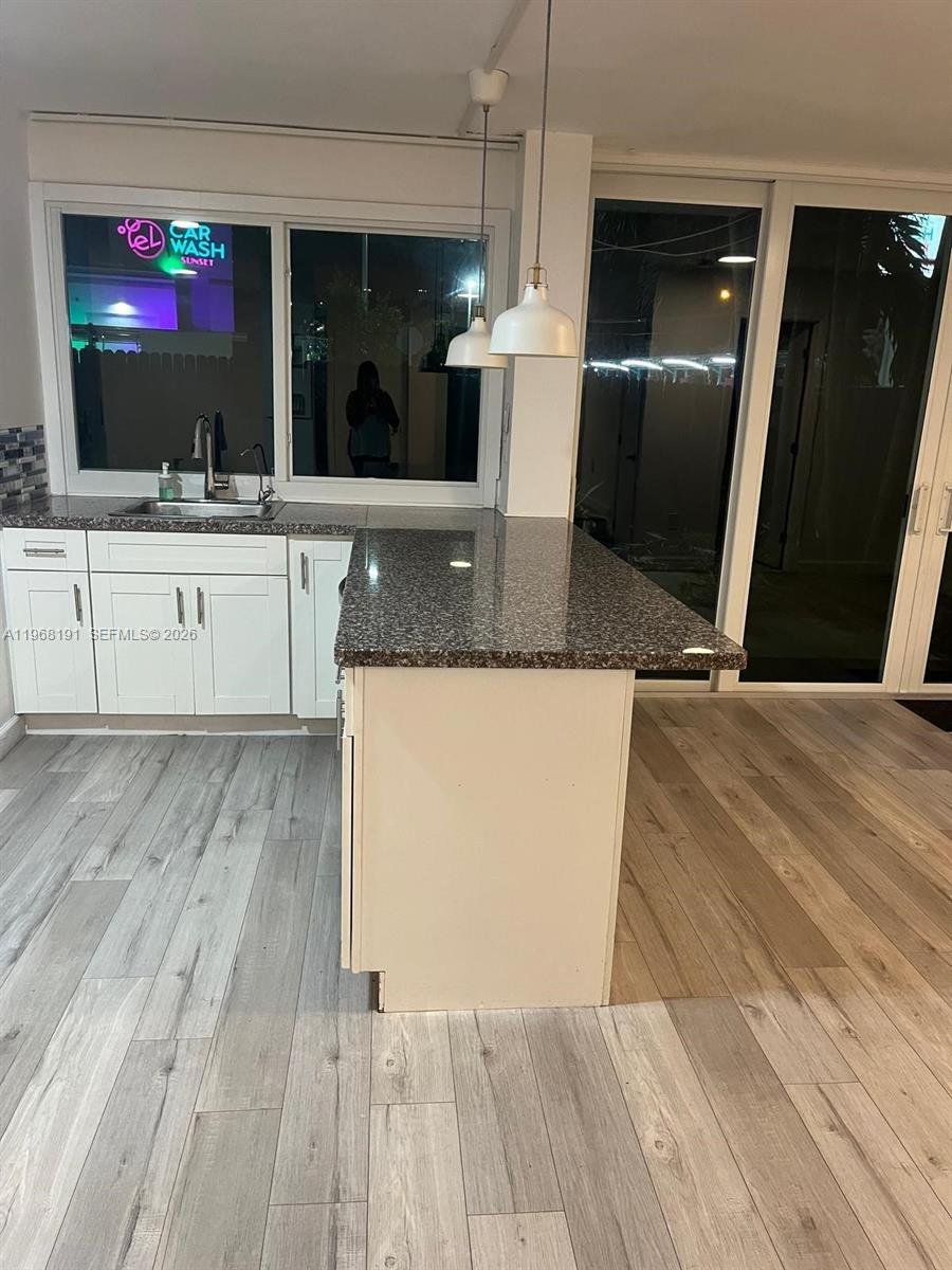 7133 Southwest 109th Court Miami, FL 33173 - Photo 4 of 13 a view of a kitchen with kitchen island a sink wooden floor and a refrigerator