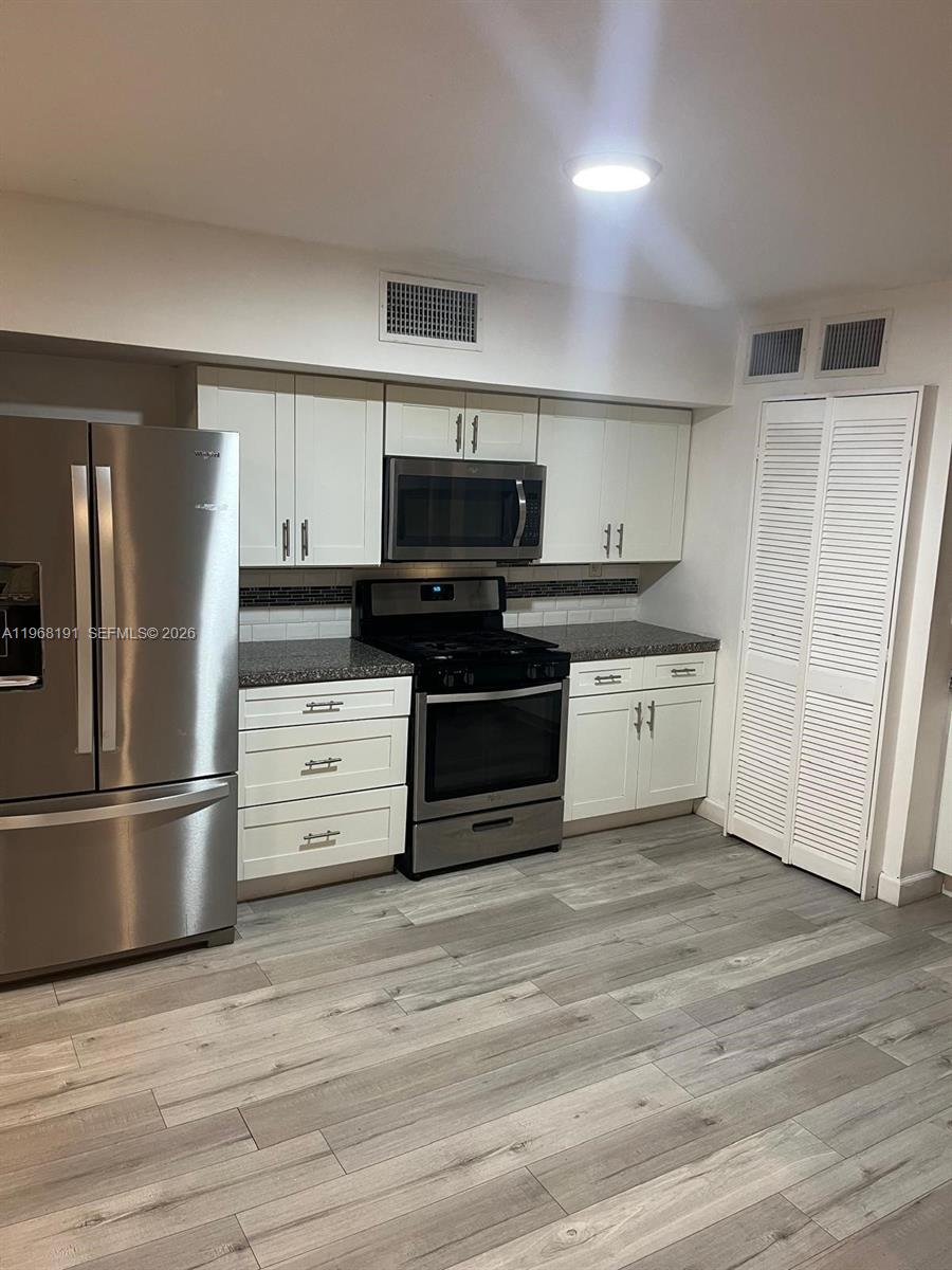 7133 Southwest 109th Court Miami, FL 33173 - Photo 6 of 13 a kitchen with stainless steel appliances a stove a refrigerator and cabinets