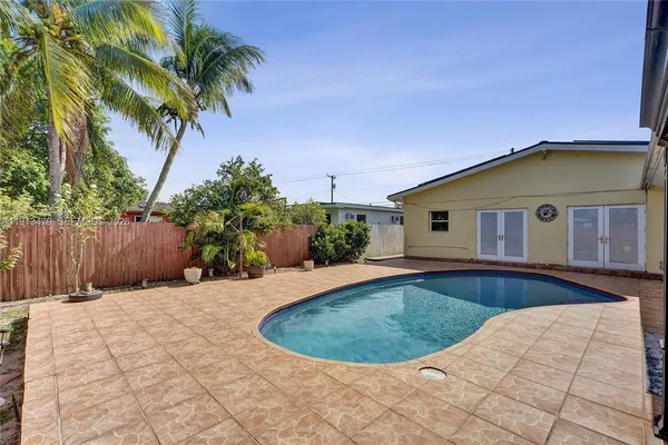 a view of a house with potted plants and a large tree