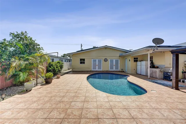 a view of a house with potted plants and a large tree