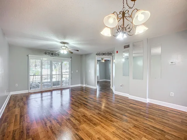 a view of an empty room with window and wooden floor