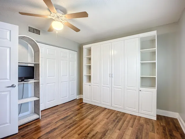a view of a livingroom with a kitchen space with wooden floor and a window