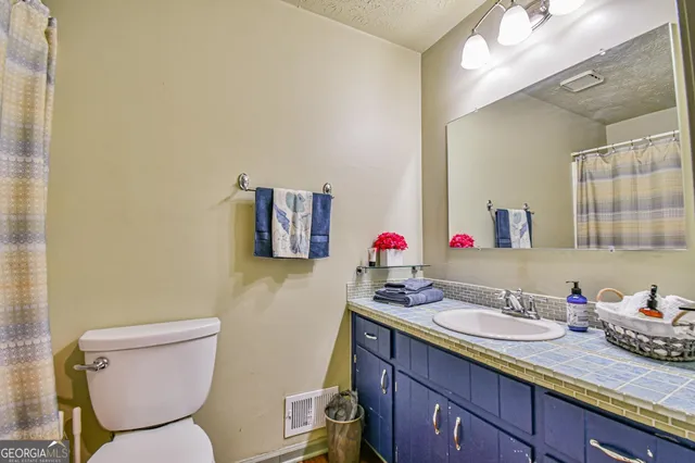 a bathroom with a granite countertop toilet sink and mirror