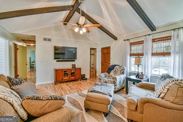 a living room with furniture a flat screen tv and a large window