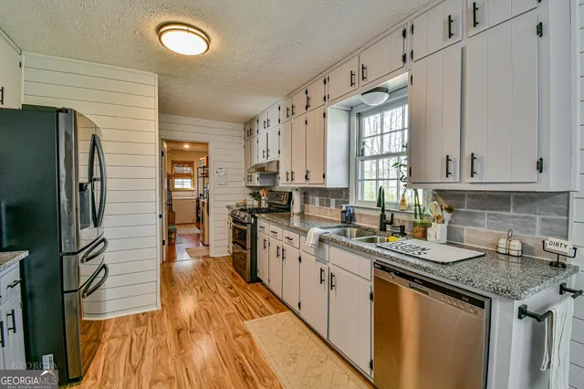 a kitchen with stainless steel appliances granite countertop a sink a stove and refrigerator