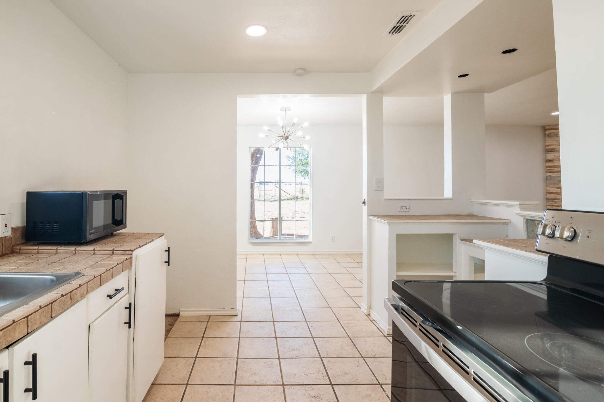 6917 Highway 114 Lubbock, TX 79407 - Photo 20 of 45 a kitchen with granite countertop a stove a sink and a microwave