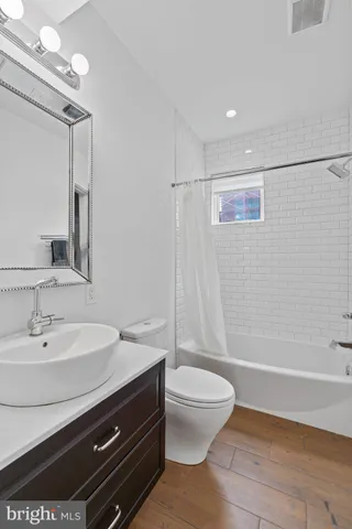 a bathroom with a bathtub shower sink vanity and toilet
