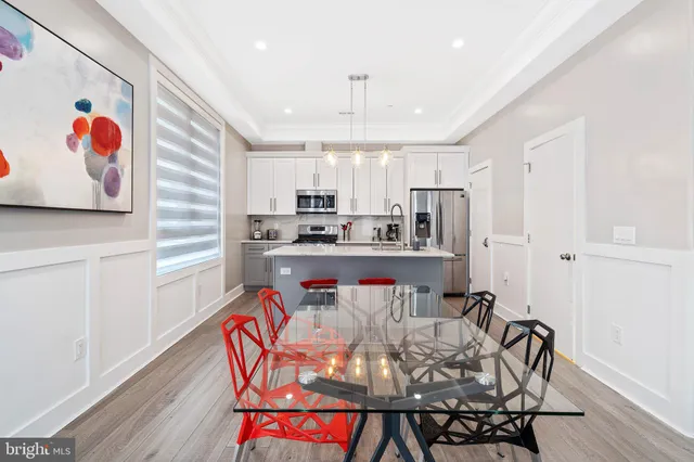 a kitchen with stainless steel appliances granite countertop a stove a refrigerator a microwave oven with white cabinets and wooden floor