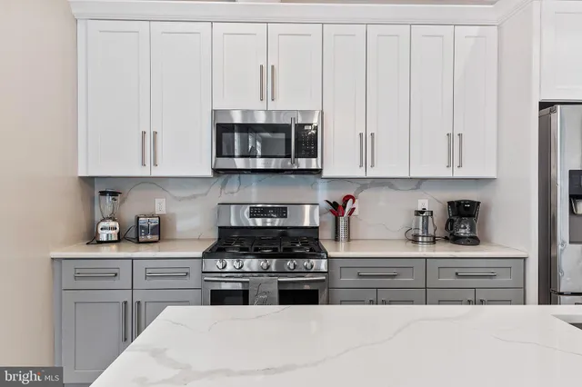 a kitchen with stainless steel appliances granite countertop a stove a sink and a white cabinets