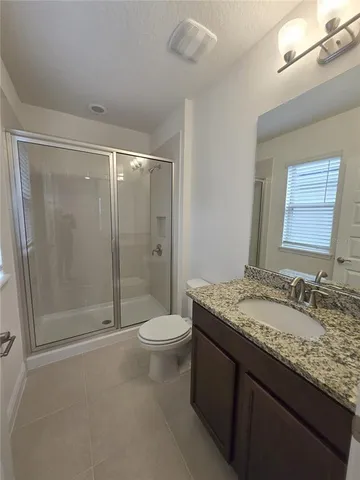 a bathroom with a granite countertop sink a toilet and a window