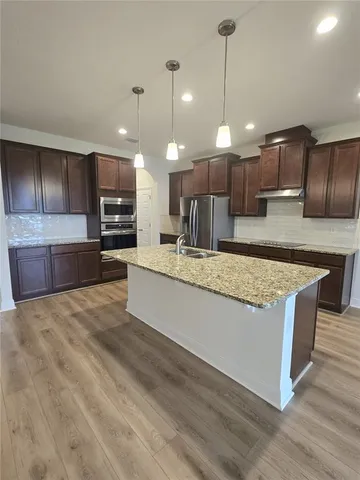 a large room with kitchen island a sink wooden floor and a chandelier