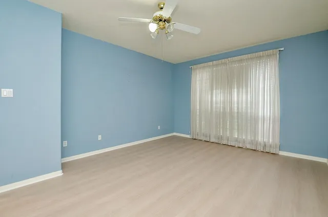 an empty room with windows and fan