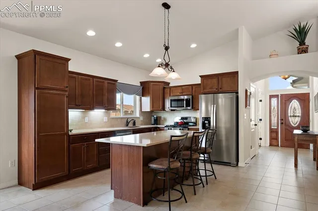 a kitchen with stainless steel appliances a refrigerator a stove a sink a dining table and chairs