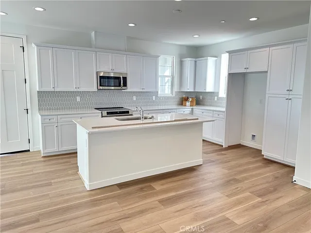 a kitchen with stainless steel appliances granite countertop a stove top oven a sink and white cabinets