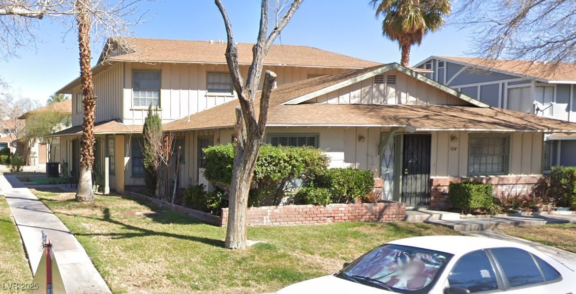 View of front of property with a shingled roof, a front lawn, and board and batten siding