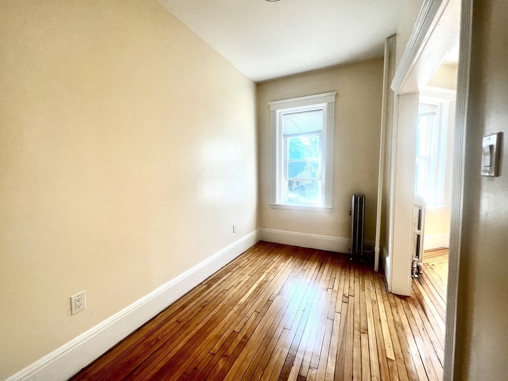 102 Trowbridge Street, Unit 2L Cambridge, MA 02138 - Photo 4 of 16 a view of an empty room with wooden floor and a window