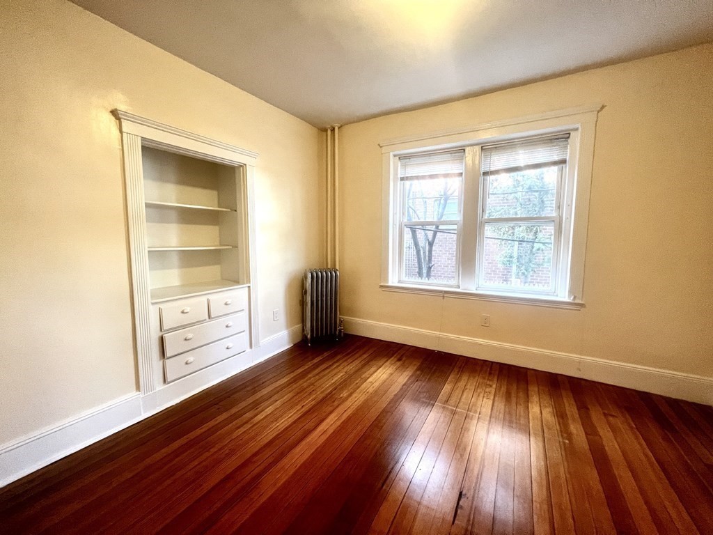 102 Trowbridge Street, Unit 2L Cambridge, MA 02138 - Photo 5 of 16 an empty room with wooden floor and windows