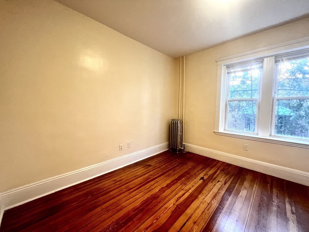 102 Trowbridge Street, Unit 2L Cambridge, MA 02138 - Photo 6 of 16 a view of an empty room with wooden floor and a window