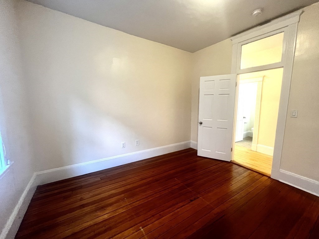 102 Trowbridge Street, Unit 2L Cambridge, MA 02138 - Photo 8 of 16 an empty room with wooden floor and windows
