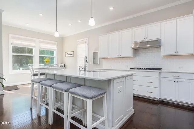 a kitchen with stainless steel appliances kitchen island granite countertop a table chairs sink and cabinets