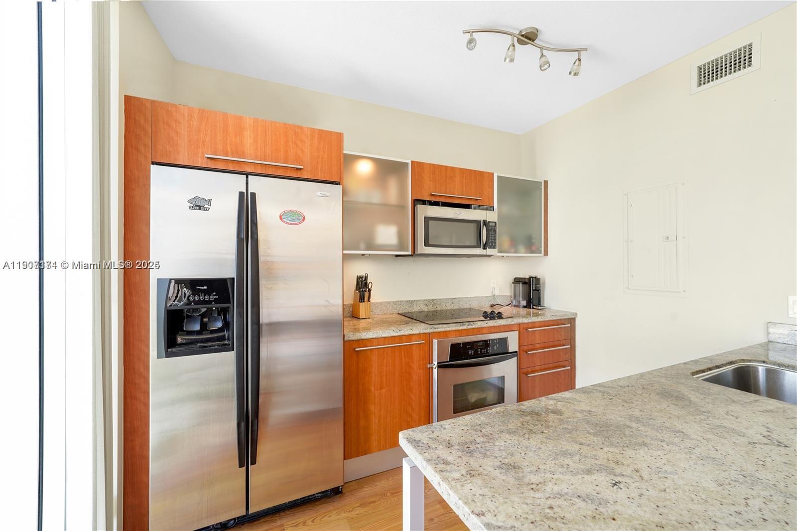 185 Southwest 7th Street, Unit 3100 Miami, FL 33130 - Photo 7 of 19 a kitchen with stainless steel appliances granite countertop a refrigerator a stove and a sink with wooden floor