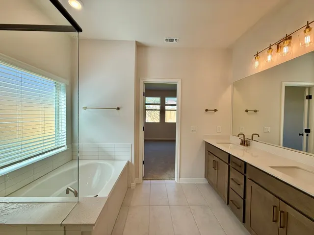 a en suite bathroom with a granite countertop tub sink and mirror