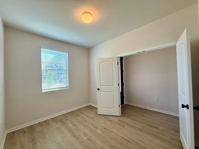 an empty room with wooden floor and window