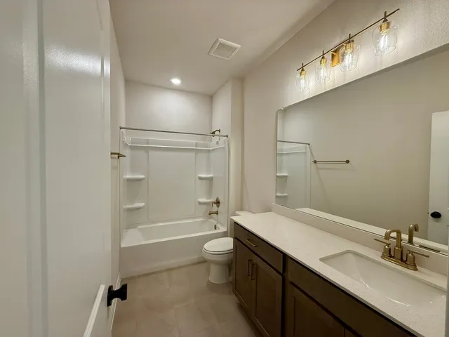 a bathroom with a bathtub shower sink vanity mirror and toilet