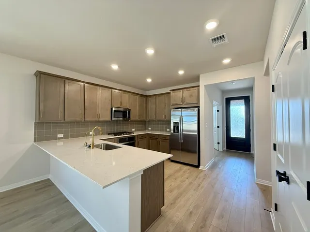 a kitchen with a sink a counter top space stainless steel appliances and wooden floor