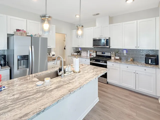 a kitchen with stainless steel appliances kitchen island granite countertop a sink refrigerator and microwave