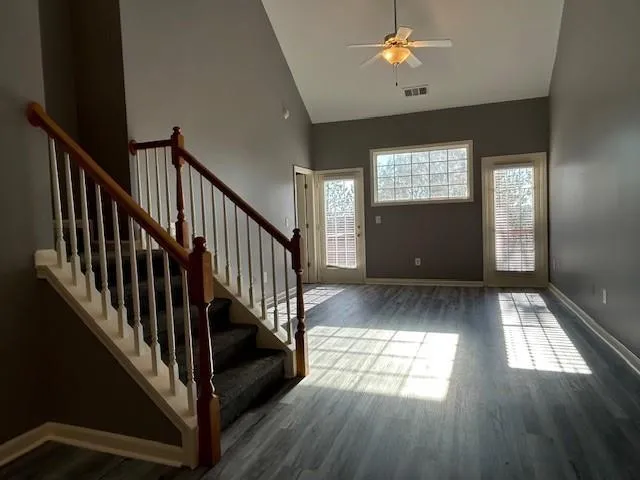 a view of staircase and kitchen with wooden floor and pendant lights