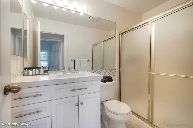 a bathroom with a sink a toilet a mirror and shower