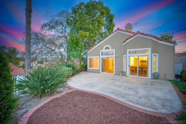 a view of a house with large trees and a small yard