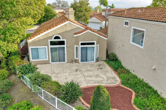 a view of a white house with a small yard and large trees