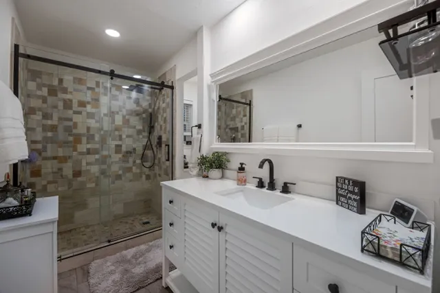 a bathroom with a shower sink vanity and mirror