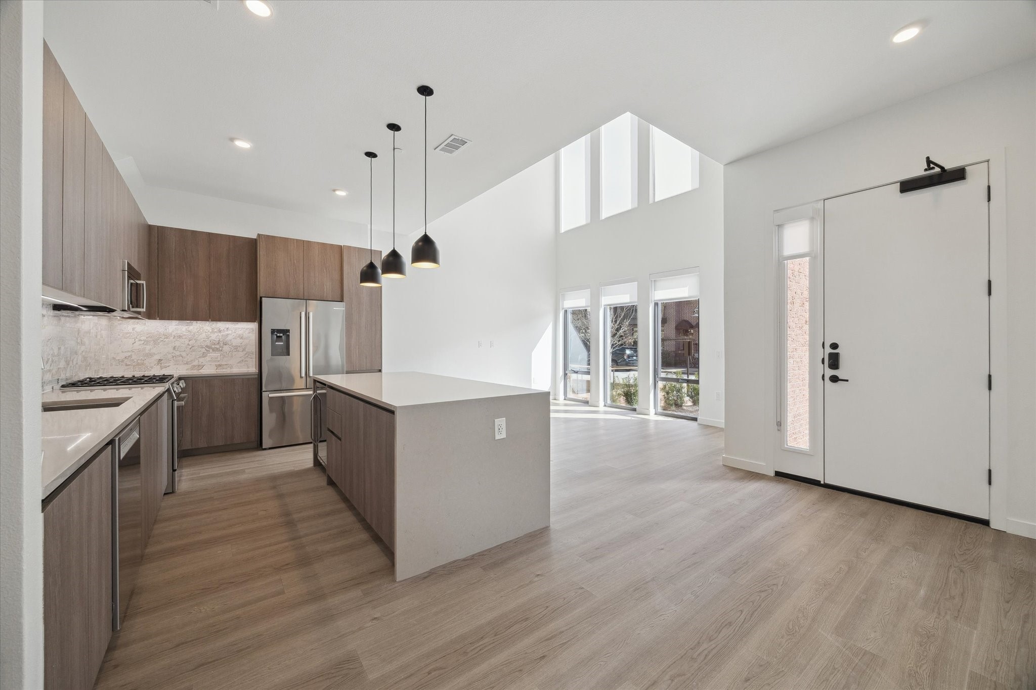 a large kitchen with granite countertop a large counter top a sink stainless steel appliances and cabinets