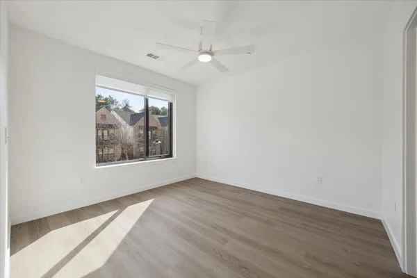 a view of an empty room with wooden floor and a window