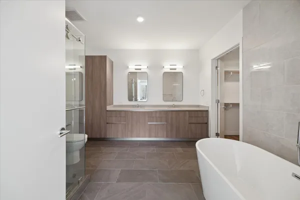 a bathroom with a tub a sink and a large mirror